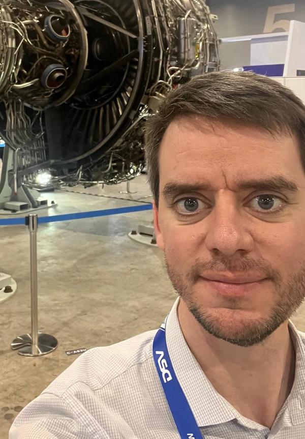 Will-Fill Sales & Marketing team member at a trade show, in front of a jet engine on display
